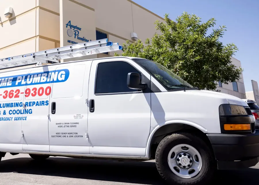 A lettered Anytime Plumbing van outside a commercial building