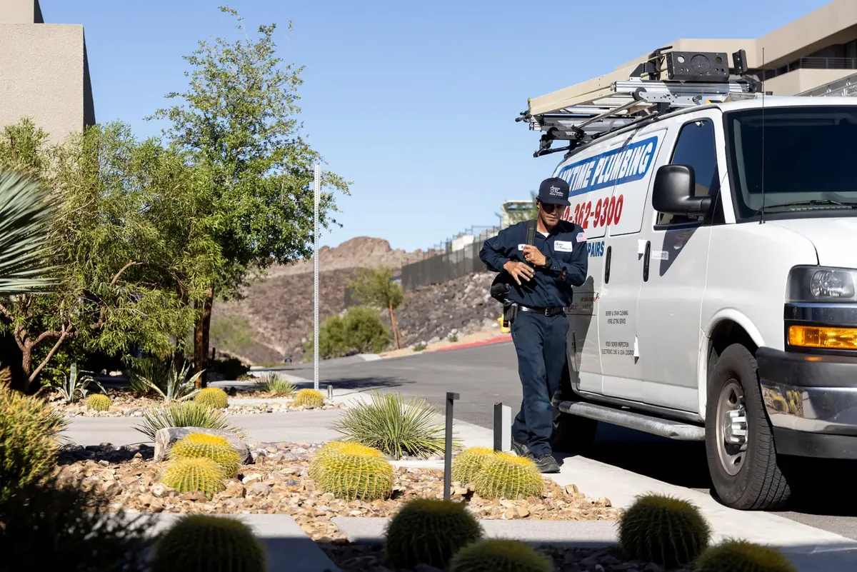 An Anytime technician walking beside a lettered company van in desert landscaping